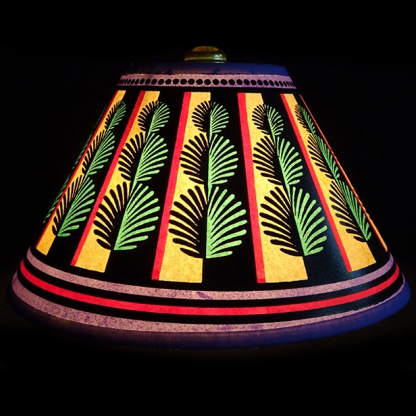 Hand painted small 10” paper empire lampshade covered in playful olive green Rows of topiary box balls running in vertical stripes around the shade contrasted by red and purple lines on a pale yellow background lit up, bringing warmth to any room